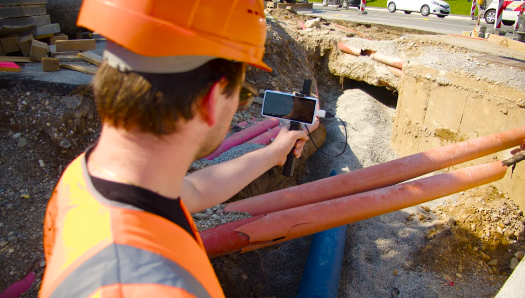 Onsite data capture with a RTK-equipped smartphone by a construction worker in an orange hardhat