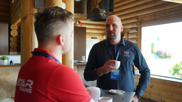 2 men talking while one drinks coffee