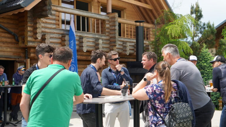People talking outside in front of a wooden building